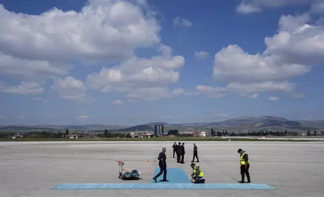 Airport workers prepare a carpet before arrival of Ukrainian President Volodymyr Zelenskyy at Esenboga airport in Ankara, Turkey, Thursday, May 15, 2025. (AP Photo/Evgeniy Maloletka)