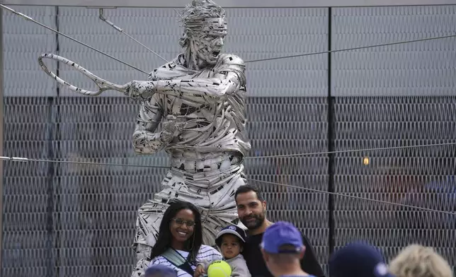 People pose for a selfie in front of a statue of Rafael Nadal, at the French Tennis Open, in the Roland-Garros stadium, in Paris, Sunday May 25, 2025. (AP Photo/Thibault Camus)