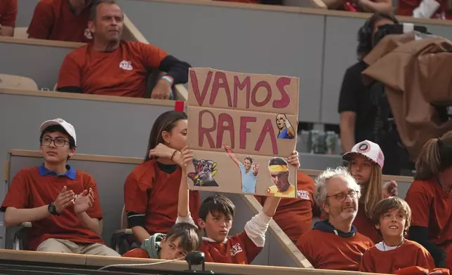 A boy holds a sign reading Vamos Rafa, ahead of a tribute to Rafa Nadal, at the French Tennis Open at the Roland Garros stadium, in Paris, Sunday May 25, 2025. (AP Photo/Lindsey Wasson)