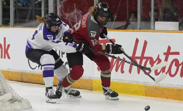 Minnesota Frost forward Dominique Petrie (14) battles Ottawa Charge forward Danielle Serdachny (92) for control of the puck behind the net during the first period of a PWHL game, Wednesday, April 30, 2025 in Ottawa. (Adrian Wyld/The Canadian Press via AP)