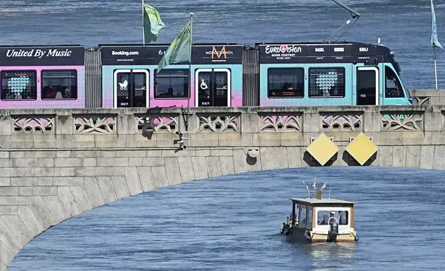 A tram with Eurovision advertising crosses the river Rhine during the 69th Eurovision Song Contest week in Basel, Switzerland, Friday May 16, 2025. (AP Photo/Martin Meissner)
