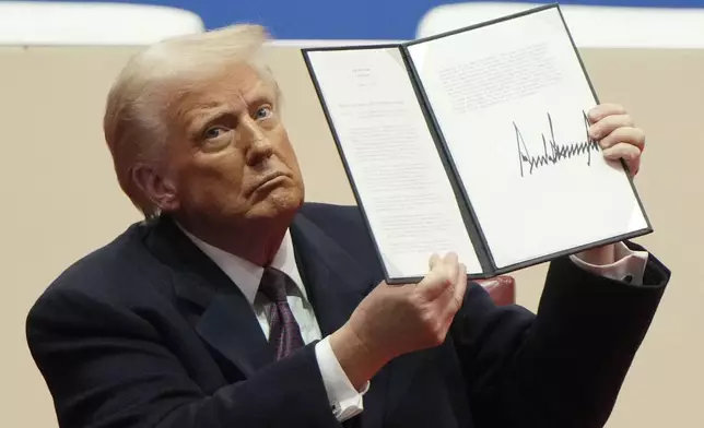 FILE - President Donald Trump holds up an executive order after signing it at an indoor Presidential Inauguration parade event in Washington, Jan. 20, 2025. (AP Photo/Matt Rourke, File)