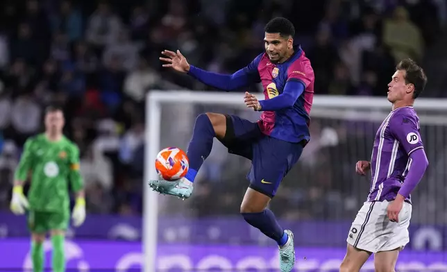 Barcelona's Ronald Araujo, centre, and Valladolid's Juanmi Latasa challenge for the ball during the Spanish La Liga soccer match between Valladolid and FC Barcelona at the Jose Zorrilla stadium in Valladolid, Spain, Saturday, May 3, 2025. (AP Photo/Manu Fernandez)