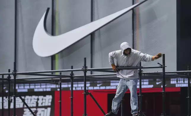 A worker installs a platform near a Nike store outside a shopping mall in Beijing, Sunday, May 11, 2025. (AP Photo/Andy Wong)