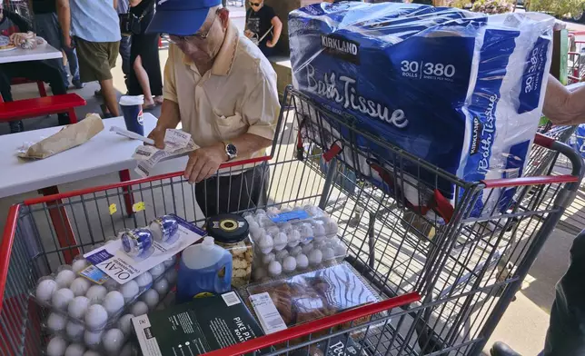 FILE - A customer checks his shopping receipts while waiting in line at the food court at Costco Wholesale store in Glendale, Calif., on Thursday, April 10, 2025. (AP Photo/Damian Dovarganes, File)