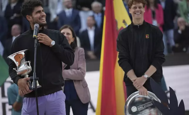 Carlos Alcaraz of Spain, holds the trophy after winning the Italian Open tennis tournament next to Jannik Sinner of Italy at the Foro Italico in Rome, Sunday, May 18, 2025. (AP Photo/Alessandra Tarantino)