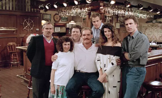 FILE -Boston Red Sox third baseman Wade Boggs, center, poses, March 2, 1988, with the cast of "Cheers" during rehearsal for an episode in which he appears. Cast members include, John Ratzenberger, Rhea Perlman, George Wendt, Woody Harrelson, Kirstie Alley and Ted Danson. (AP Photo/Ira Mark Gostin, File)