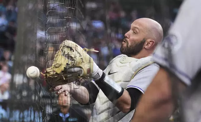 Colorado Rockies catcher Jacob Stallings runs out of room in a failed attempt to make a catch on a foul ball hit by Arizona Diamondbacks' Eugenio Suárez during the first inning of a baseball game Friday, May 16, 2025, in Phoenix. (AP Photo/Ross D. Franklin)