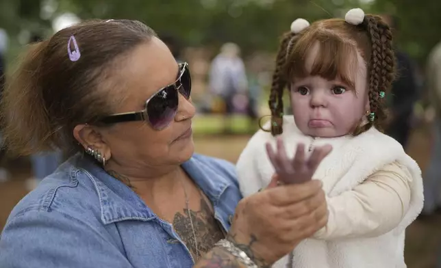 Nice Maria Santos holds her doll during a group gathering to bond and show off their hyper-realistic reborn baby dolls, in a park in Sao Paulo, Saturday, May 24, 2025. (AP Photo/Andre Penner)