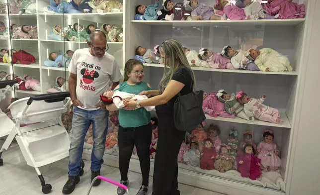 A family shops for a hyper-realistic reborn babydoll at a shopping mall in Campinas, Brazil, Saturday, May 24, 2025. (AP Photo/Andre Penner)