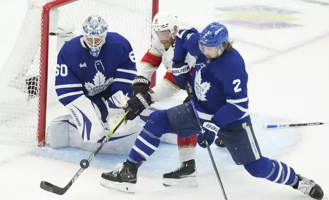 Florida Panthers centre Sam Bennett (9) and Toronto Maple Leafs defenceman Simon Benoit (2) vie for control of the puck in front of Leafs goalie Joseph Woll (60) during the second period of an NHL Stanley Cup playoff hockey game in Toronto, Sunday, May 18, 2025. (Chris Young/The Canadian Press via AP)