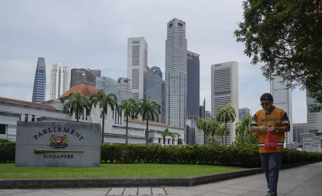 Pedestrian walks in front of the parliament building in Singapore, Friday, May 2, 2025. (AP Photo/Vincent Thian)