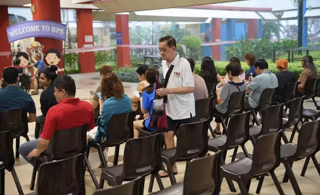 Singaporean voters arrives at a voting station to cast their vote for general election in Singapore, Saturday, May 3, 2025. (AP Photo/Vincent Thian)