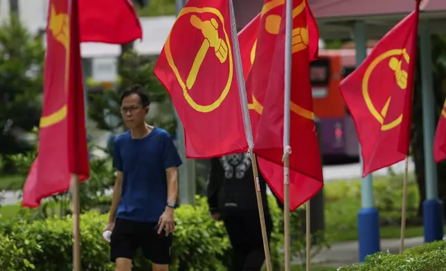 A man walks next to workers' party flags at Hougang area in Singapore, Friday, May 2, 2025. (AP Photo/Vincent Thian)