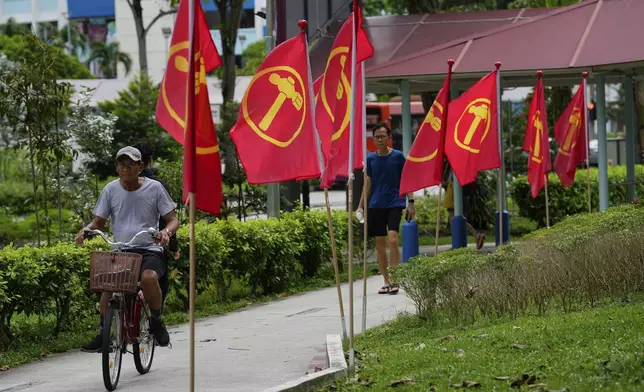 A Singaporean rides his bike next workers' party flags at Hougang area in Singapore, Friday, May 2, 2025. (AP Photo/Vincent Thian)