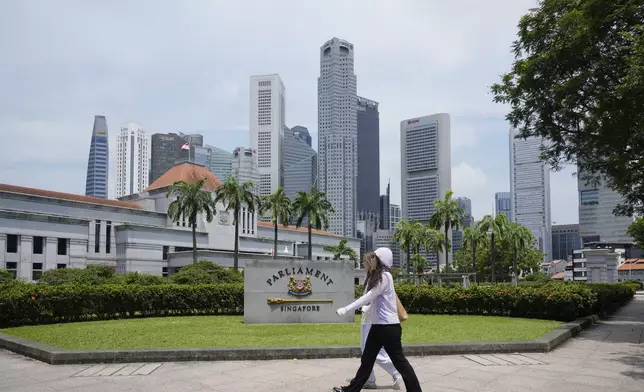 Pedestrians walk in front of the parliament building in Singapore, Friday, May 2, 2025. (AP Photo/Vincent Thian)