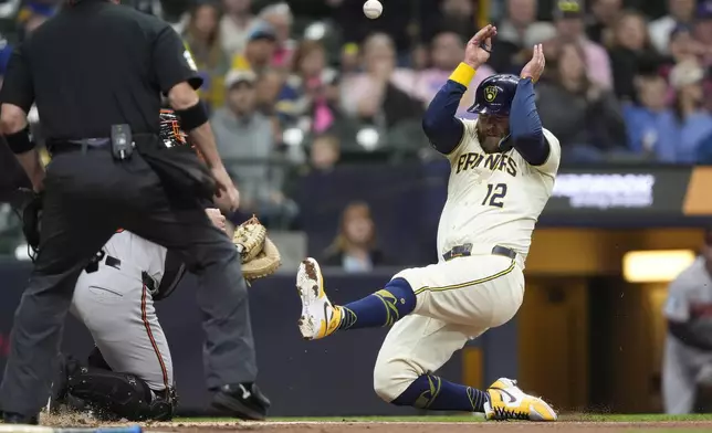 Milwaukee Brewers' Rhys Hoskins (12) slides into home to score during the second inning of a baseball game against the Baltimore Orioles, Monday, May 19, 2025, in Milwaukee. (AP Photo/Aaron Gash)