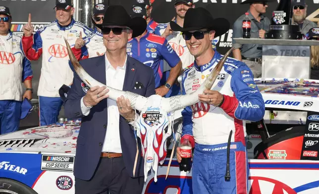 Joey Logano, right, poses with a cow skull Wurth 400 trophy in Victory Lane tafter winning a NASCAR Cup Series auto race at Texas Motor Speedway in Fort Worth, Texas, Sunday, May 4, 2025. (AP Photo/Gareth Patterson)