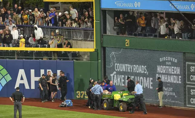 A fan is carted off the field at PNC Park after falling out of the stands during the seventh inning of a baseball game between the Pittsburgh Pirates and the Chicago Cubs in Pittsburgh, Wednesday, April 30, 2025. (AP Photo/Gene J. Puskar)