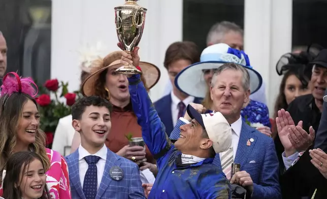 Junior Alvarado holds the trophy as he celebrates after riding Sovereignty to victory in the 151st running of the Kentucky Derby horse race at Churchill Downs Saturday, May 3, 2025, in Louisville, Ky. (AP Photo/Brynn Anderson)