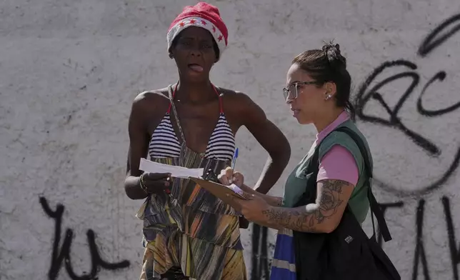 A city health worker interviews a drug user in a downtown area popularly known as "Crackland" in Sao Paulo, Tuesday, May 20, 2025. (AP Photo/Andre Penner)