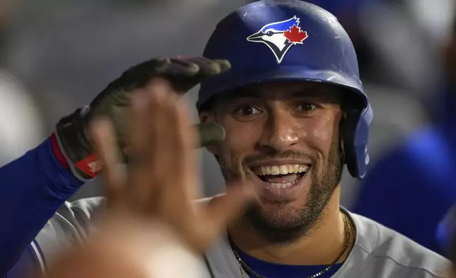 Toronto Blue Jays' George Springer celebrates with teammates in the dugout after scoring on a throwing error by Los Angeles Angels catcher Logan O'Hoppe during the sixth inning of a baseball game Thursday, May 8, 2025, in Anaheim, Calif. (AP Photo/Mark J. Terrill)