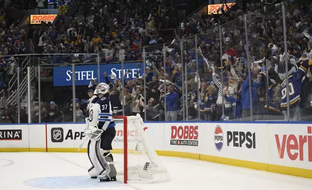 St. Louis Blues fans react as Winnipeg Jets goaltender Connor Hellebuyck (37) looks on during the second period in Game 6 of an NHL hockey first-round playoff series against the Winnipeg Jets, Friday, May 2, 2025, in St. Louis. (AP Photo/Jeff Le)