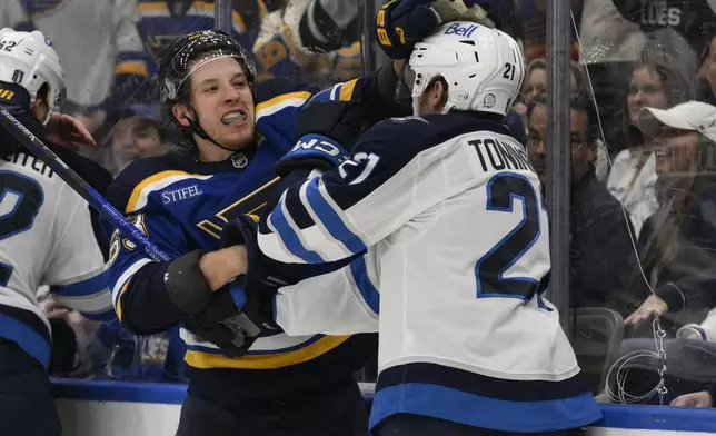 St. Louis Blues left wing Jake Neighbours, second from right, gets physical with Winnipeg Jets center Dominic Toninato, right, during the third period in Game 6 of an NHL hockey first-round playoff series Friday, May 2, 2025, in St. Louis. (AP Photo/Jeff Le)