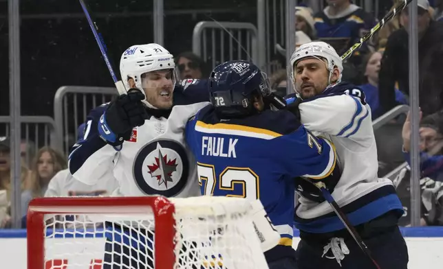 Winnipeg Jets center Dominic Toninato, left, and right wing Nino Niederreiter, right, get physical with St. Louis Blues defenseman Justin Faulk, center, during the third period in Game 6 of an NHL hockey first-round playoff series Friday, May 2, 2025, in St. Louis. (AP Photo/Jeff Le)