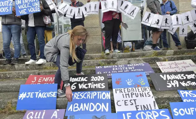 People place posters during a demonstration ahead of the verdict in the trial of Joel Le Scouarnec, a 74-year-old former surgeon, accused of raping and sexually assaulting 299 children, Wednesday, May 28, 2025 in Vannes, Brittany, western France. (AP Photo/Mathieu Pattier)
