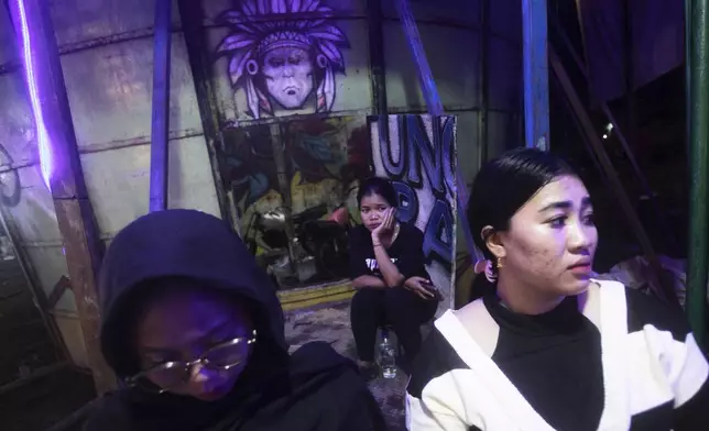 "Wall of death" riders Sri Wahyuni, who is also known as Ayu, right, and Rismauly Girsang, center, take a break between performances at a fairground in Medan, North Sumatra, Indonesia, Saturday, May 10, 2025. (AP Photo/Binsar Bakkara)