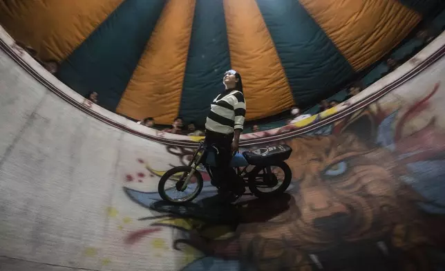 Sri Wahyuni, who is also known by her nickname Ayu, rides a motorcycle in the "wall of death," locally known as "tong setan" or satan's barrel, at a fairground in Medan, North Sumatra, Indonesia, Saturday, May 10, 2025. (AP Photo/Binsar Bakkara)