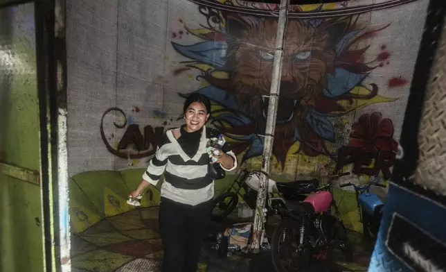 Sri Wahyuni, also known as Ayu, walks with tip money in her hands after a performance in the "wall of death," locally known as "tong setan" or satan's barrel, at a fairground in Medan, North Sumatra, Indonesia, Saturday, May 10, 2025. (AP Photo/Binsar Bakkara)