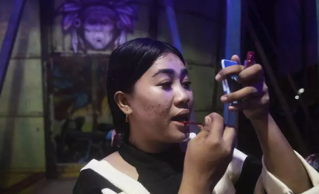 Sri Wahyuni, also known as Ayu, applies make up before performing in the "wall of death", locally known as "tong setan" or satan's barrel, at a fairground in Medan, North Sumatra, Indonesia, Saturday, May 10, 2025. (AP Photo/Binsar Bakkara)