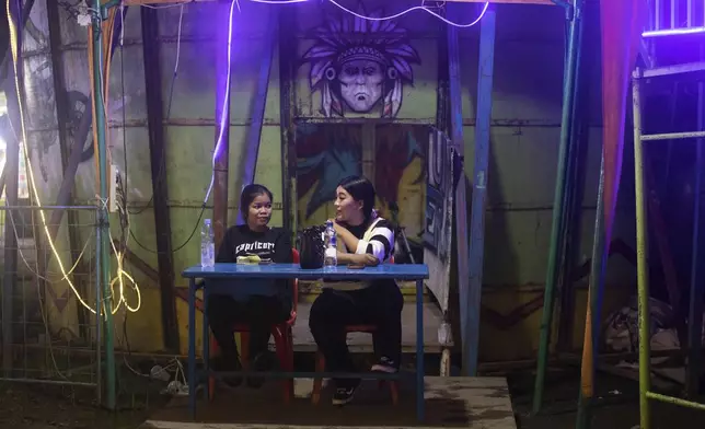 Sri Wahyuni, also known by her nickname Ayu, right, and Rismauly Girsang, both 'wall of death' riders, chat during a break between performances at a fairground in Medan, North Sumatra, Indonesia, Saturday, May 10, 2025. (AP Photo/Binsar Bakkara)