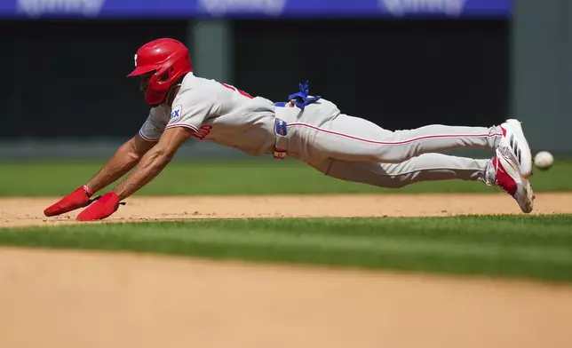 Philadelphia Phillies' Johan Rojas dives safely into second base for a stolen base against the Colorado Rockies during the ninth inning of a baseball game Thursday, May 22, 2025, in Denver. (AP Photo/Jack Dempsey)