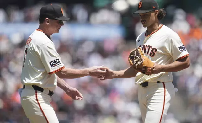 San Francisco Giants pitcher Jordan Hicks, right, hands the ball to manager Bob Melvin during a making a pitching change in the third inning of a baseball game against the Arizona Diamondbacks in San Francisco, Wednesday, May 14, 2025. (AP Photo/Jeff Chiu)
