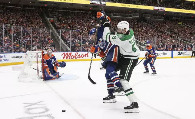 Dallas Stars' Lian Bichsel (6) and Edmonton Oilers' John Klingberg, center left, battle for the puck during the third period of Game 3 of the NHL hockey Stanley Cup Western Conference finals in Edmonton, Alberta, Sunday, May 25, 2025. (Jason Franson/The Canadian Press via AP)