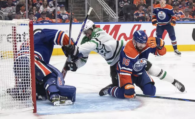 Dallas Stars' Mason Marchment (27) and Edmonton Oilers' Jake Walman (96) battle as Oilers goalie Stuart Skinner, left, makes a save during the third period of Game 3 of the NHL hockey Stanley Cup Western Conference finals in Edmonton, Alberta, Sunday, May 25, 2025. (Jason Franson/The Canadian Press via AP)