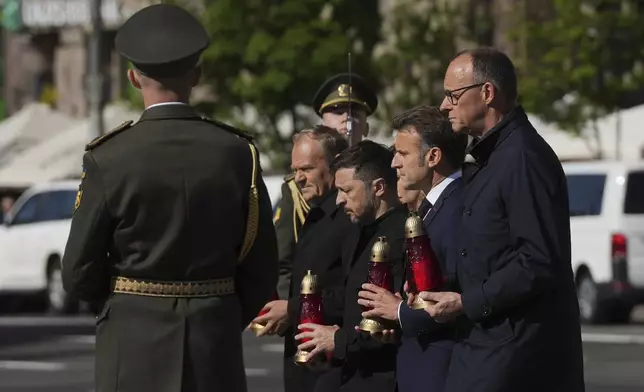 From left, Polish Prime Minister Donald Tusk, Ukrainian President Volodymyr Zelenskyy, French President Emmanuel Macron and German Chancellor Friedrich Merz, carry candles at the memorial of fallen Ukrainian soldiers at independence square in Kyiv, Ukraine, on Saturday, May 10, 2025. (AP Photo/Evgeniy Maloletka)