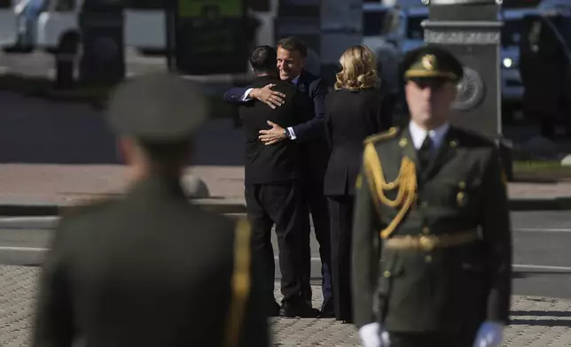 Ukrainian President Volodymyr Zelenskyy hugs French President Emmanuel Macron at the memorial of fallen Ukrainian soldiers at independence square in Kyiv, Ukraine, on Saturday, May 10, 2025. (AP Photo/Evgeniy Maloletka)
