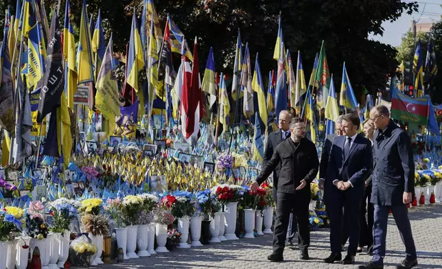 From left, Poland's Prime Minister Donald Tusk, Ukraine's President Volodymyr Zelensky, Britain's Prime Minister Keir Starmer, France's President Emmanuel Macron, Olena Zelenska and Germany's Chancellor Friedrich Merz pay their respects to the victims of war at the Memorial for the Fallen at the Independence Square in Kyiv, Saturday, May 10, 2025, where all three will hold meetings with Ukrainian President Volodymyr Zelenskyy Friday, May 9, 2025. (Ludovic Marin, Pool Photo via AP)