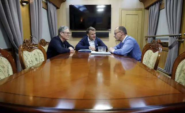 Britain's Prime Minister Keir Starmer, left, meets with French President Emanuel Macron, center, and German Chancellor Friedrich Merz onboard a train to Kyiv, in Shegyni, Ukraine, where all three will hold meetings with Ukrainian President Volodymyr Zelenskyy Friday, May 9, 2025. (Ludovic Marin, Pool Photo via AP)