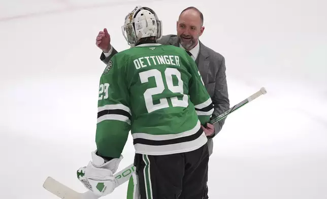 Dallas Stars goaltender Jake Oettinger (29) and head coach Pete DeBoer, rear, celebrate the teams 4-2 win against the Colorado Avalanche in Game 7 of a first-round NHL hockey playoff series Saturday, May 3, 2025, in Dallas. (AP Photo/Julio Cortez)
