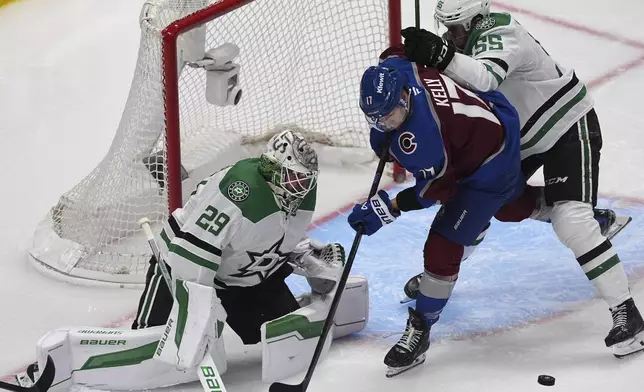 Colorado Avalanche center Parker Kelly, center, struggles to collect the puck as Dallas Stars defenseman Thomas Harley, right, and goaltender Jake Oettinger cover in the third period of Game 6 of an NHL first-round hockey playoff series Thursday, May 1, 2025, in Denver. (AP Photo/David Zalubowski)