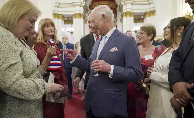 Britain's King Charles III speaks to guests during a reception in Buckingham Palace, London, in celebration of community-based initiatives raising awareness about cancer and supporting those living with cancer, Wednesday April 30, 2025. (Yui Mok/Pool Photo via AP)