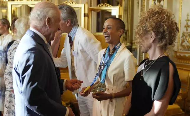 Britain's King Charles III speaks with broadcaster Adele Roberts during a reception in Buckingham Palace, London, in celebration of community-based initiatives raising awareness about cancer and supporting those living with cancer, Wednesday April 30, 2025. (Andrew Matthews/Pool Photo via AP)