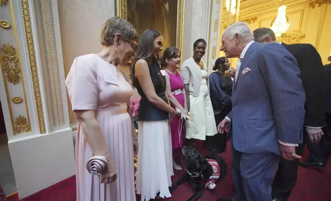 Britain's King Charles III greets Vicky Pattison during a reception in Buckingham Palace, London, in celebration of community-based initiatives raising awareness about cancer and supporting those living with cancer, Wednesday April 30, 2025. (Yui Mok/Pool Photo via AP)