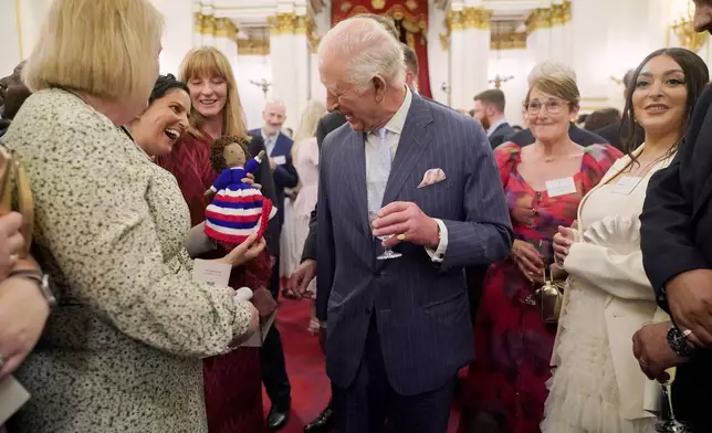 Britain's King Charles III speaks to guests during a reception in Buckingham Palace, London, in celebration of community-based initiatives raising awareness about cancer and supporting those living with cancer, Wednesday April 30, 2025. (Yui Mok/Pool Photo via AP)