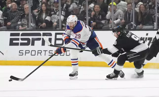 Edmonton Oilers center Leon Draisaitl, left, passes the puck while under pressure from Los Angeles Kings right wing Adrian Kempe during the third period in Game 5 of an NHL hockey first-round playoff series Tuesday, April 29, 2025, in Los Angeles. (AP Photo/Mark J. Terrill)
